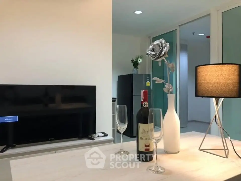 Modern living room with stylish decor, featuring a TV, wine setup, and elegant lighting.