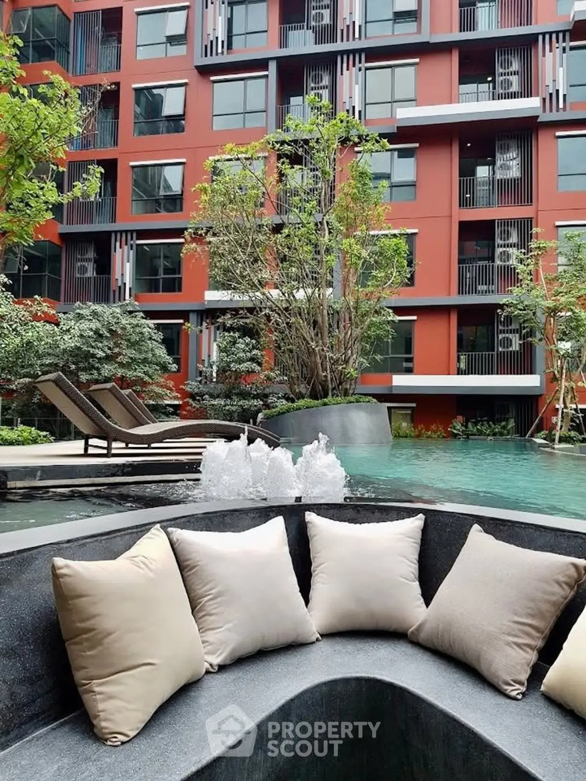 Luxurious apartment complex with poolside seating and modern architecture.