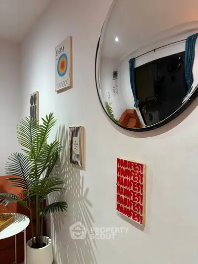 Stylish living room with modern decor and unique wall art, featuring a round mirror and vibrant plant.