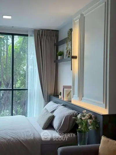 Elegant bedroom with large window and modern decor, featuring cozy bed and stylish shelving.