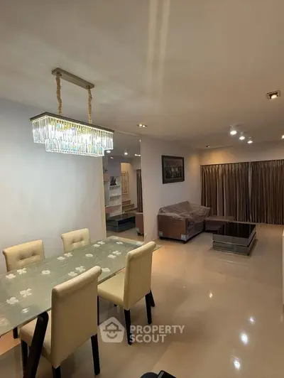 Elegant living and dining area with modern chandelier and cozy seating.