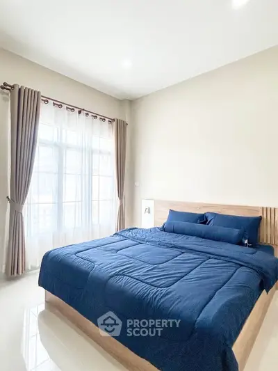 Spacious bedroom with large window and elegant blue bedding
