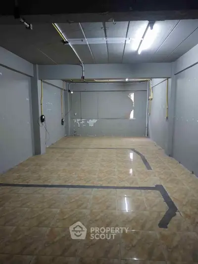 Spacious empty room with tiled flooring and exposed wiring, ideal for customization.