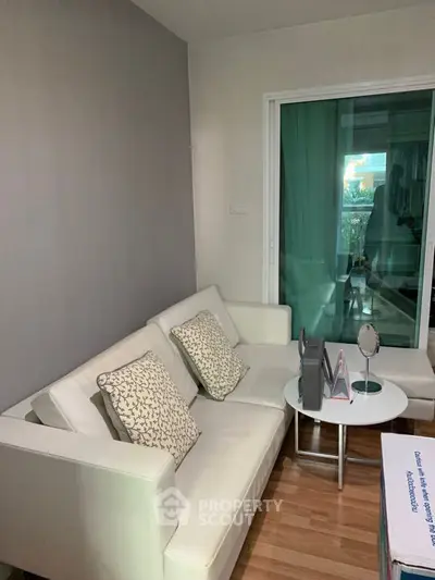Cozy modern living room with sleek white sofa set, warm wooden flooring, and access to a sunlit balcony, perfect for urban living.
