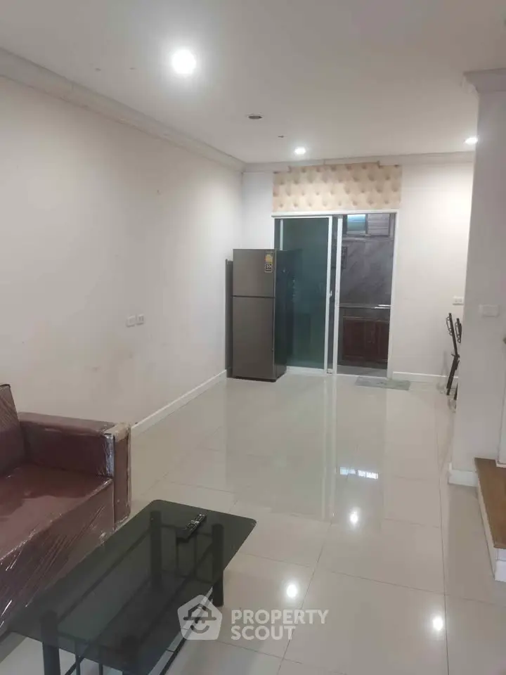 Spacious living room with modern furniture and a sleek refrigerator, perfect for contemporary living.