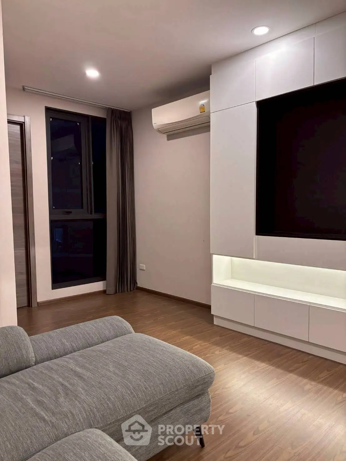 Modern living room with sleek furniture and built-in storage unit.