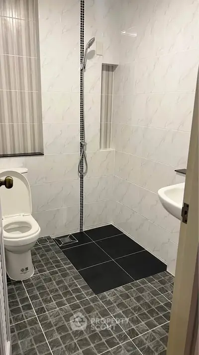 Modern bathroom with sleek tiles and shower area in a real estate property.