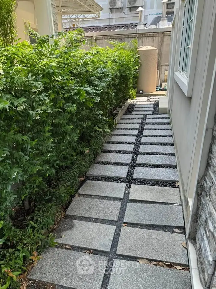 Charming garden pathway with modern stone tiles and lush greenery, perfect for serene outdoor living.