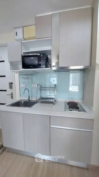 Modern compact kitchen with sleek cabinetry and built-in appliances in a stylish apartment.