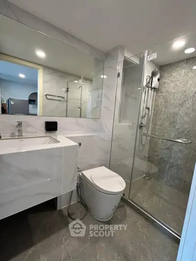Modern bathroom with sleek design, featuring a glass shower enclosure and contemporary fixtures.