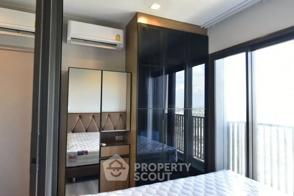Modern bedroom with large windows and mirrored wardrobe in high-rise apartment