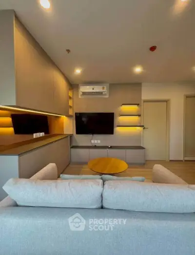 Modern living room with sleek design, featuring a wall-mounted TV and stylish lighting.