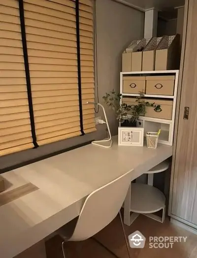 Elegant home office nook with a sleek white desk, modern chair, and tasteful storage solutions, complemented by warm wooden blinds.