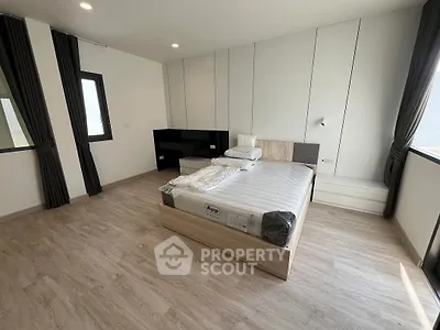 Spacious modern bedroom with sleek design and ample natural light, featuring a comfortable bed and stylish flooring.