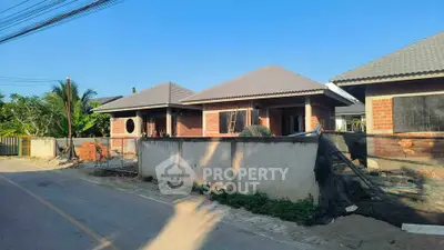 Charming suburban house under construction with brick facade and modern roof design.
