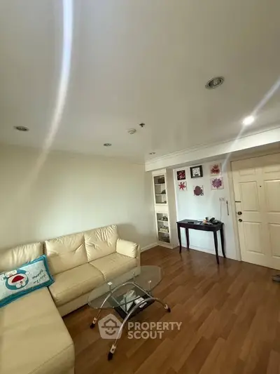 Cozy living room with beige sofa and wooden flooring, perfect for relaxation.