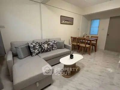 Modern living room with stylish gray sofa and elegant dining area in open layout apartment.