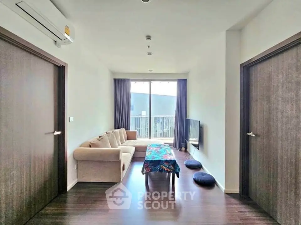 Modern living room with cozy sofa, stylish decor, and large window offering natural light.