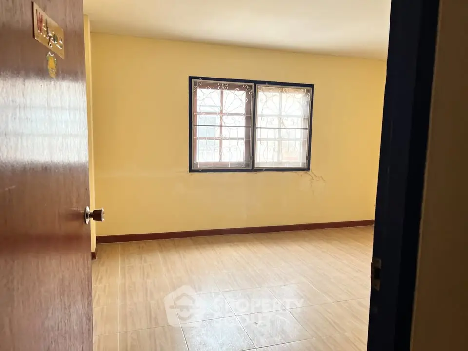 Spacious empty room with large window and wooden flooring, perfect for customization.