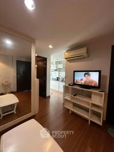 Cozy living room with TV, air conditioning, and modern kitchen in open layout apartment.