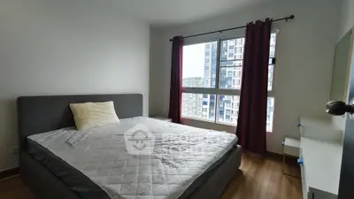 Spacious bedroom with large window offering city views, featuring a comfortable bed and modern decor.