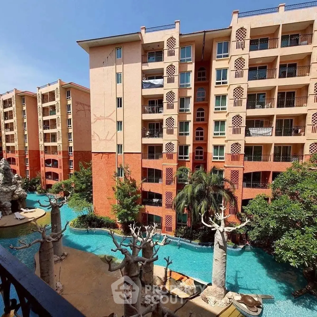 Stunning view of a modern apartment complex with a large swimming pool and lush greenery.