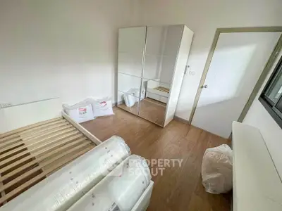 Cozy bedroom with wooden flooring and mirrored wardrobe in modern apartment