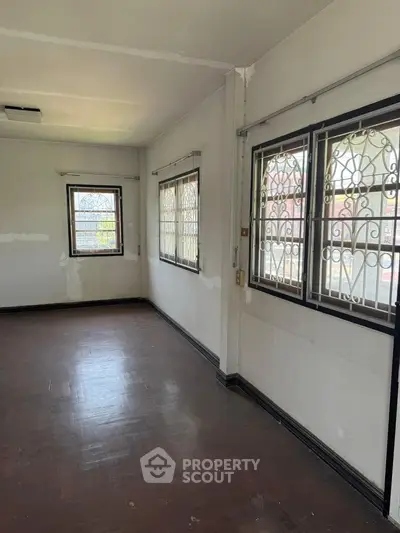 Spacious room with large windows and wooden flooring, ideal for customization and renovation.