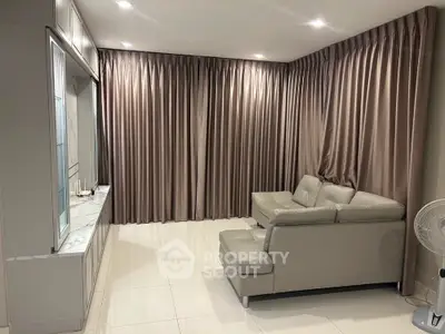 Modern living room with sleek gray sofa and elegant floor-to-ceiling curtains
