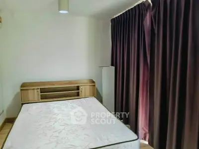 Cozy bedroom with large window and dark curtains, featuring a wooden headboard and comfortable mattress.