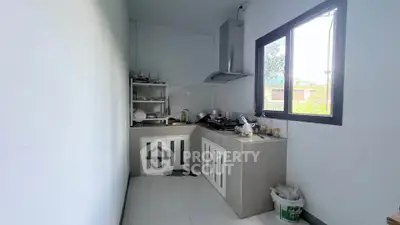 Modern minimalist kitchen with sleek cabinetry and large window offering natural light.