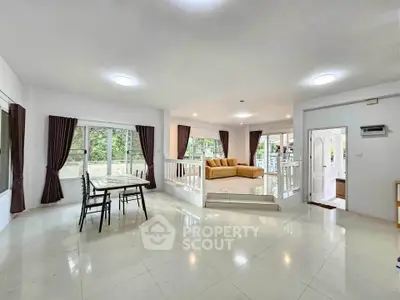 Spacious open-plan living room with large windows and elegant dining area