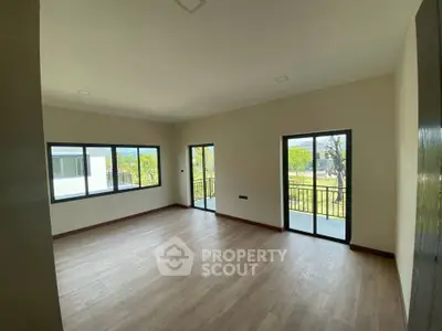 Spacious living room with large windows and balcony access, offering abundant natural light.