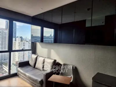 Modern living room with city view, featuring sleek black furniture and large windows.