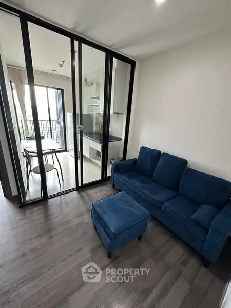 Modern living room with blue sofa and glass partition leading to dining area