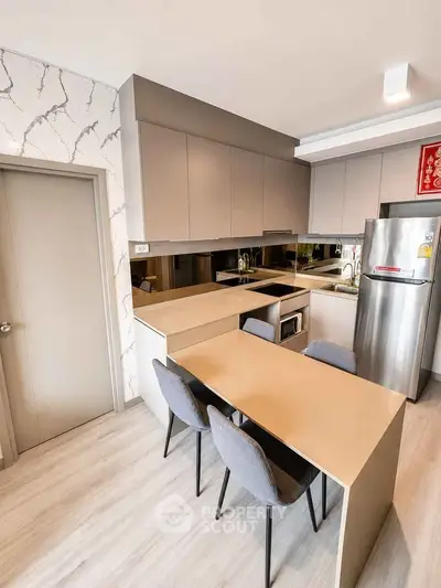 Modern kitchen with sleek cabinetry and integrated dining area in contemporary apartment.