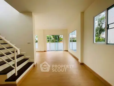 Spacious open-plan living area with large windows and wooden flooring, perfect for modern living.