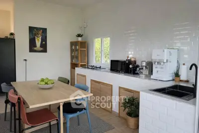 Modern kitchen with sleek appliances and stylish dining area, featuring a unique cat portrait for a touch of charm.