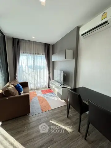 Modern living room with natural light, sleek furniture, and air conditioning in a stylish apartment.