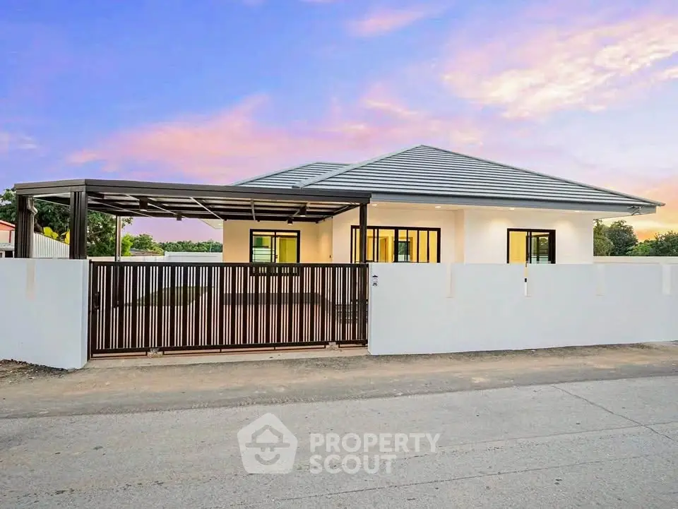 Modern single-story house with sleek design and spacious carport at sunset.