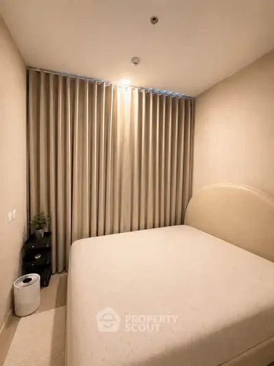 Cozy bedroom with elegant curtains and minimalist decor, perfect for restful nights.