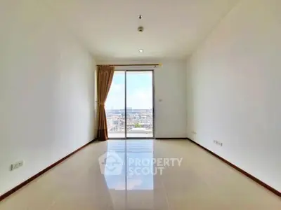 Spacious empty room with large window offering panoramic city view.