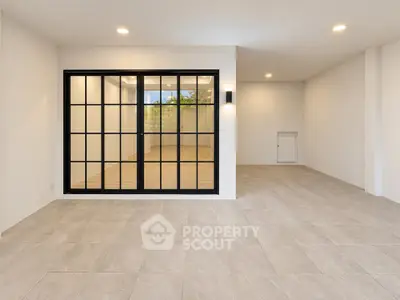Spacious modern living room with large glass doors and elegant tile flooring.