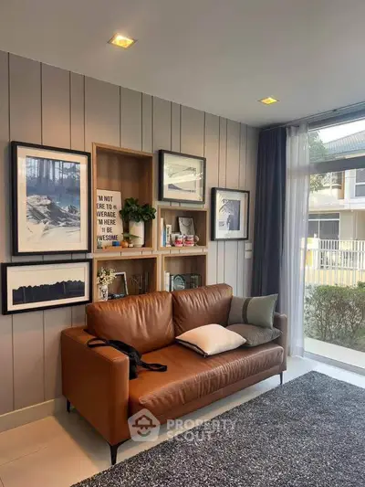 Stylish living room with leather sofa and modern decor, featuring large window view.