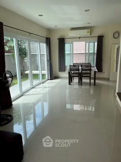 Spacious dining area with large windows and garden view, perfect for family gatherings.