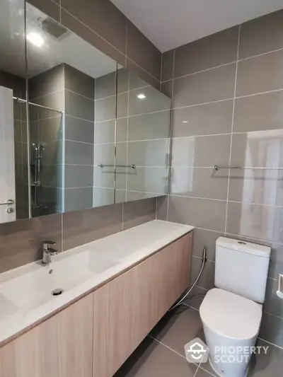 Modern bathroom with sleek vanity and large mirror in contemporary apartment.