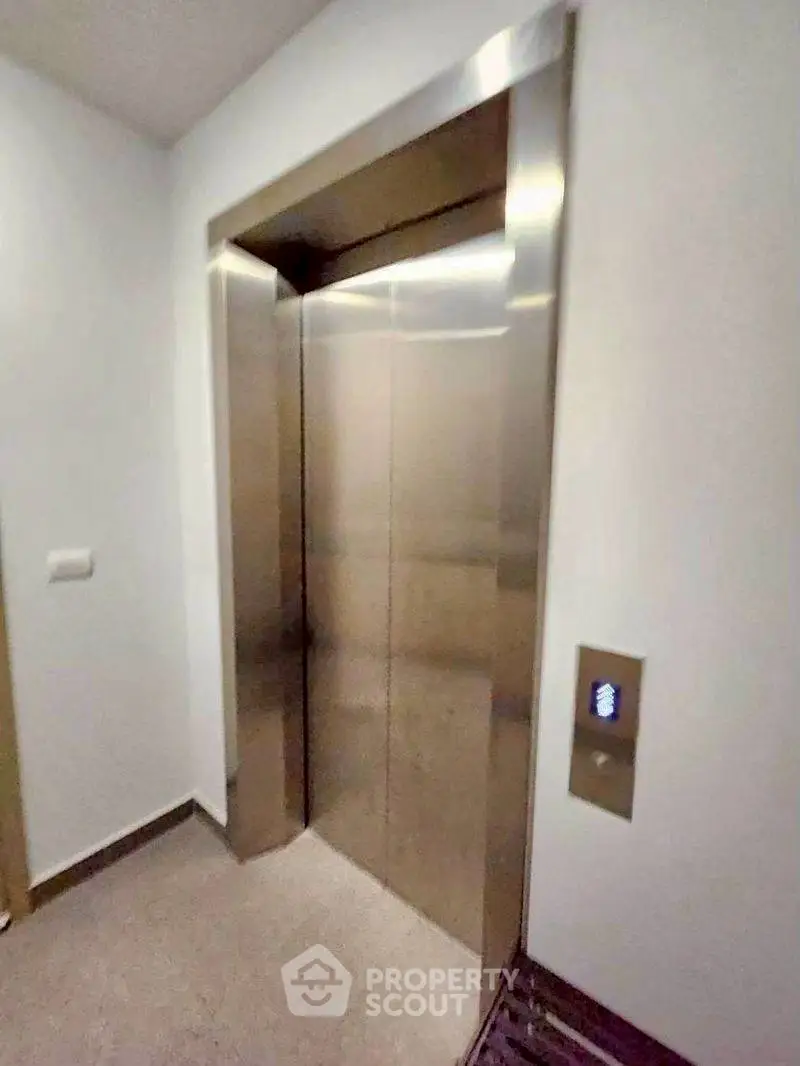 Modern elevator in a sleek residential building with stainless steel doors and contemporary design.