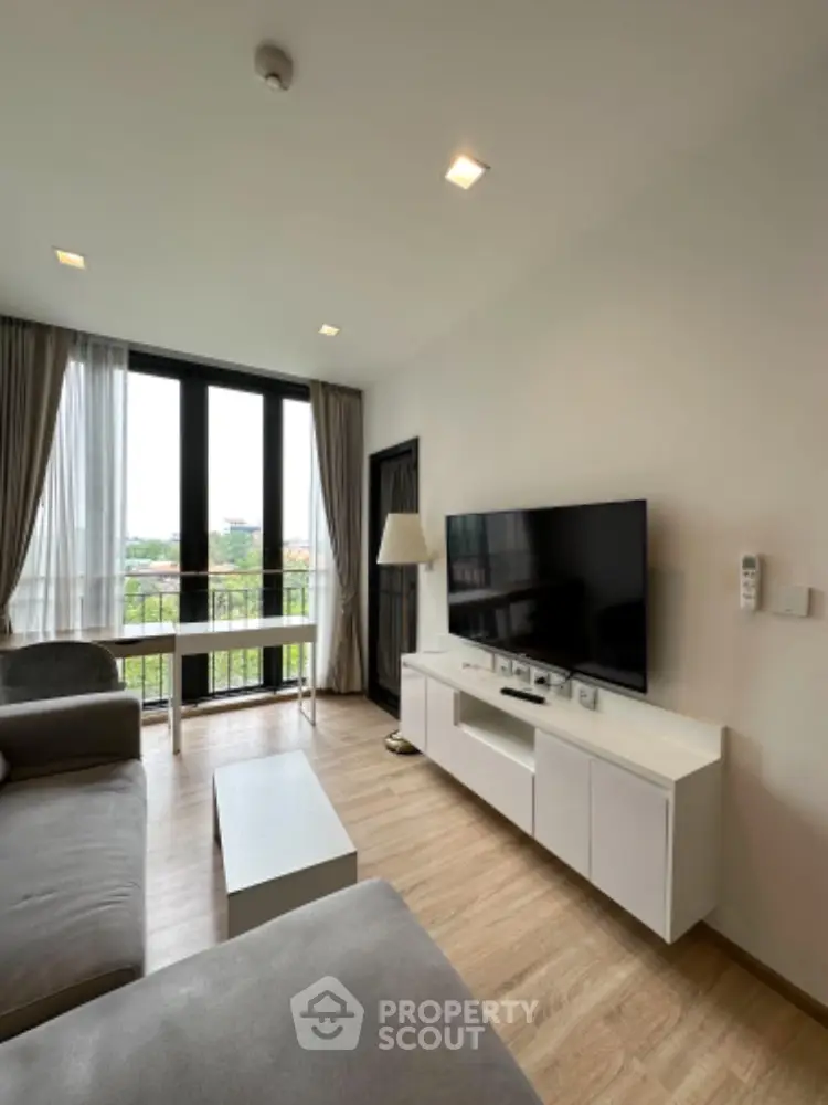 Spacious modern living room with abundant natural light, sleek furnishings, and access to a breezy balcony with a serene view, perfect for urban living.