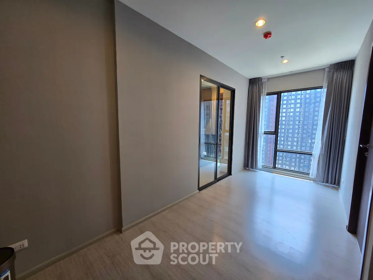 Spacious modern apartment with large windows and balcony view in urban setting.
