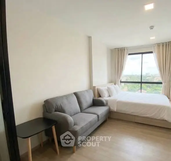 Modern bedroom with cozy sofa and large window offering scenic view